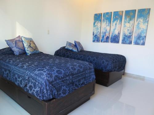 a bedroom with two beds and paintings on the wall at Apartamento en la playa en Mazatlán in Mazatlán