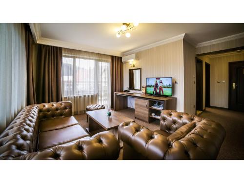 a living room with leather furniture and a flat screen tv at Park Hotel and SPA Vella Hills in Velingrad