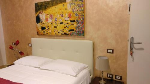 a bedroom with a white bed and a painting on the wall at Casamare Hotel in San Vincenzo