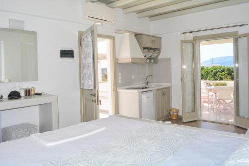 a white room with a bed and a kitchen at Notos Studios in Schinoussa