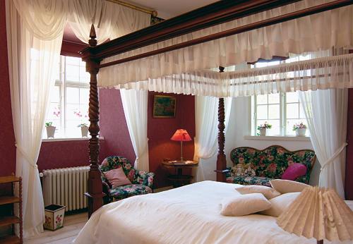 a bedroom with a canopy bed and two chairs at Broholm Castle in Gudme
