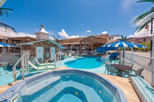 a pool at a resort with a table and umbrella at Expedition Lodge Moab Arches National Park in Moab