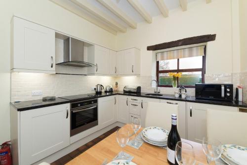 a kitchen with white cabinets and a table with wine glasses at Conwy Valley Cottages in Conwy