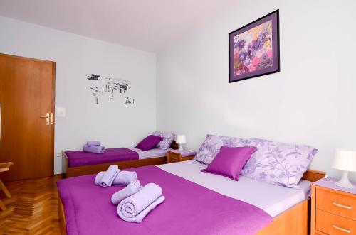 a bedroom with two beds with purple sheets and towels at Apartments Amico in Zadar