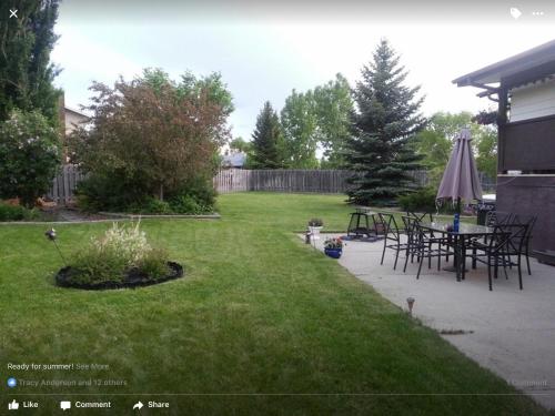 a yard with a table and chairs and an umbrella at Newly Renovated Basement Suite! in Lethbridge