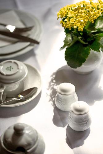 a table with plates and a vase with yellow flowers at Hotel Villa Königsgarten in Siebeldingen