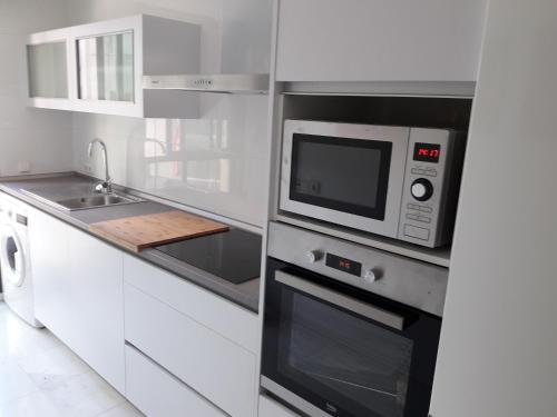 una cucina bianca con forno a microonde e lavandino di Apartamento Las 4 Palmeras a Cordoba