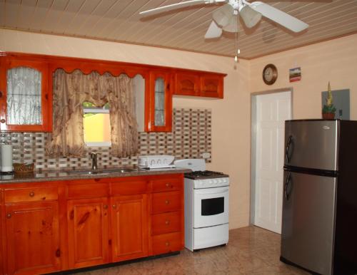 eine Küche mit Holzschränken und einem Kühlschrank in der Unterkunft Green Haven Cottage in Les Coteaux