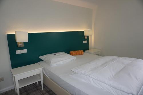 a bedroom with a white bed with a green headboard at Landgasthof Läuterhäusle in Aalen