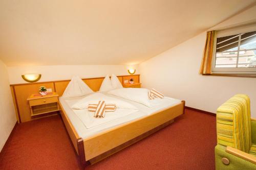 ein Schlafzimmer mit einem großen Bett und einem gelben Stuhl in der Unterkunft Appartement Jagdhof in Flachau