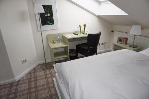 a bedroom with a bed and a desk with a chair at Landgasthof Läuterhäusle in Aalen