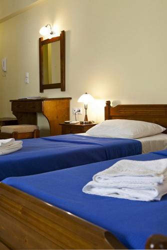 a bedroom with two beds with blue sheets and a mirror at Evangelia in Ayia Evfimia