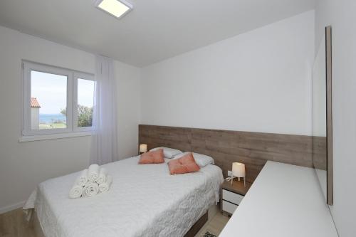a white bedroom with two beds and a window at Valadar Apartments in Privlaka