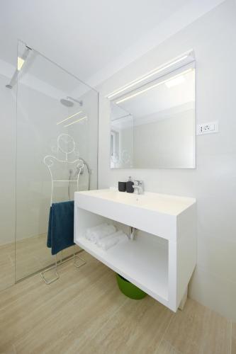 a white bathroom with a sink and a mirror at Valadar Apartments in Privlaka