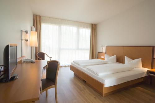 a bedroom with a bed and a desk and a television at Hotel der Rastanlage im Hegau OST in Engen