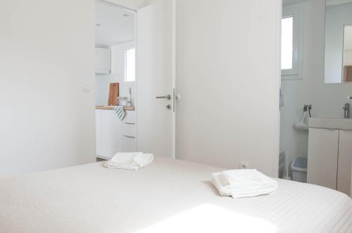 een witte slaapkamer met een bed met twee handdoeken erop bij First apartment Zadar in Zadar
