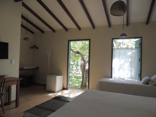 a bedroom with a bed and a window with a giraffe outside at Pousada Chica Pitanga in São Miguel do Gostoso