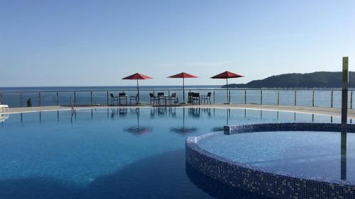 a swimming pool with tables and umbrellas on the beach at ApartHotel Belvedere Residence Becici Budva in Budva
