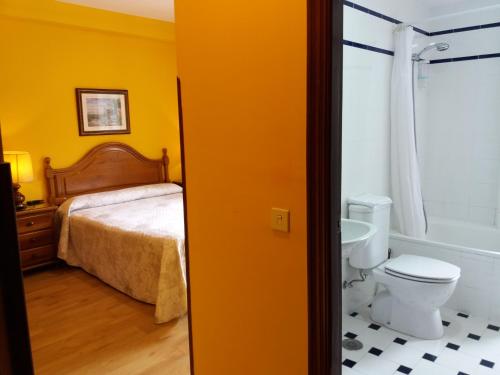a bedroom with a bed and a bathroom with a toilet at Pension Monteverde in Cangas de Onís