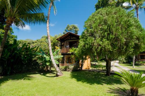 a house in the middle of a yard with palm trees at Pousada Atlântida in Arraial d'Ajuda