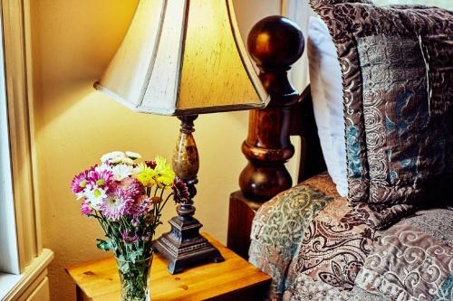 a vase of flowers on a table next to a lamp at Andon-Reid Inn Bed & Breakfast in Waynesville