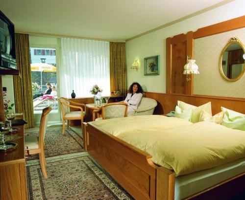 una donna seduta in una camera con un grande letto di Hotel Traube a Bad Wildbad