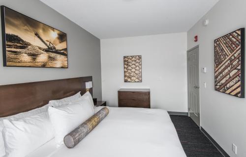 a bedroom with a large white bed with a wooden headboard at Edgewater Hotel in Whitehorse