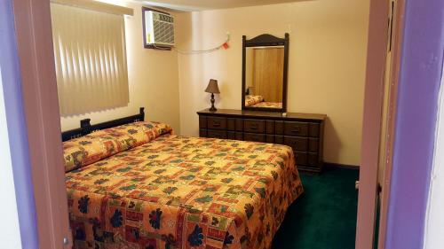 a bedroom with a bed and a dresser and a mirror at Westernaire Motel in Mesa