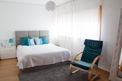 a bedroom with a bed and a green chair at Alto das Marinhas in Aveiro