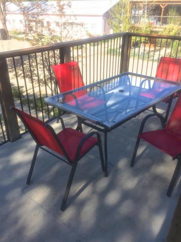 a glass table and two red chairs on a balcony at Mancos Inn in Mancos