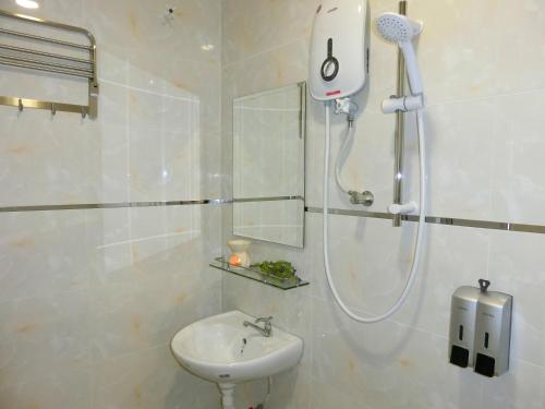 een witte badkamer met een douche en een wastafel bij Carlsun Hotel in Kulai