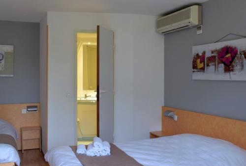 a hotel room with two beds and a mirror at Fasthôtel - Saint Emilion Est in Montcaret