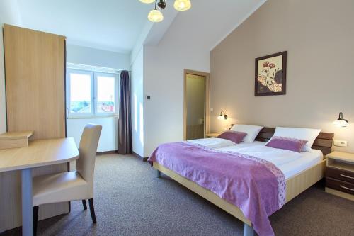 a bedroom with a bed and a desk and a computer at Hotel Villa Margaret in Malinska