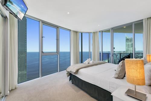 a bedroom with a bed and large glass windows at Orchid Residences - HR Surfers Paradise in Gold Coast