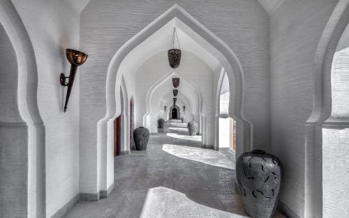 a hallway with white walls and an archway at Evolve Back Hampi in Hampi