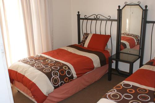 a bedroom with two twin beds and a mirror at Eric's Apartments in Centurion