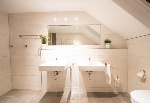 Baño con 2 lavabos y espejo en Hotel Restaurant Litermont, en Nalbach