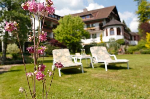a group of chairs sitting in the grass in front of a house at Hotel Waldblick Kniebis in Kniebis