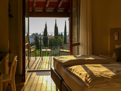 a bedroom with a bed and a balcony with a view at Hotel Relais Agli Olivi in Lazise