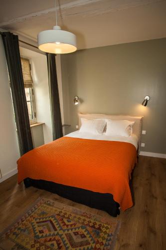 a bedroom with a bed with an orange blanket at Maison d'hôtes les Escures in Acigné