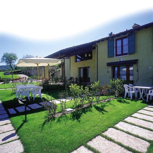a house with an umbrella and a table and chairs at Residence Corte Camaldoli in Garda