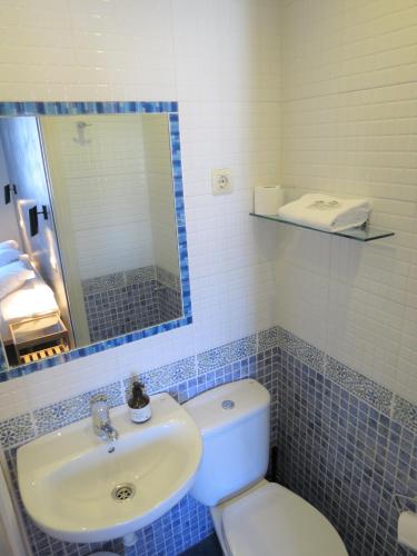 a bathroom with a sink and a toilet and a mirror at Pensión Don Claudio in Bilbao