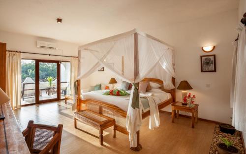 a bedroom with a bed with a canopy at Ocean Village Club (Adults Only) in Diani Beach