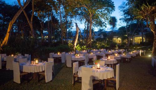 a group of tables with white chairs and candles at Ocean Village Club (Adults Only) in Diani Beach