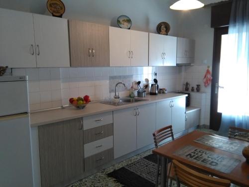 a kitchen with white cabinets and a table and a sink at Olena House in Kavala