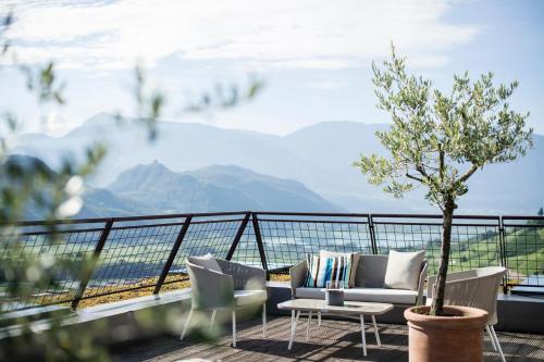 a balcony with a couch and chairs and a tree at Designhotel Gius La Residenza in Caldaro