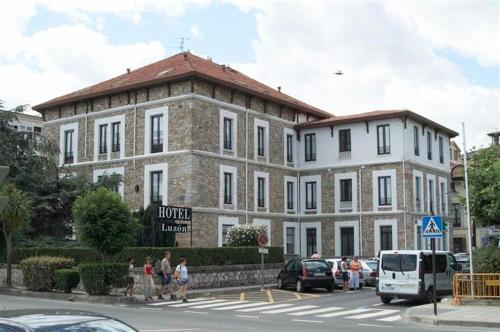 een groot bakstenen gebouw waar mensen voor lopen bij Hotel Luzon in San Vicente de la Barquera