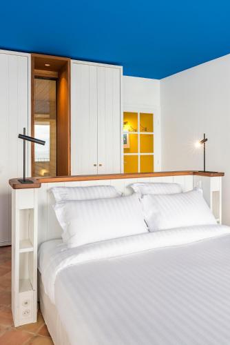 a large white bed in a room with white cabinets at Hôtel Le Bailli De Suffren in Rayol-Canadel-sur-Mer