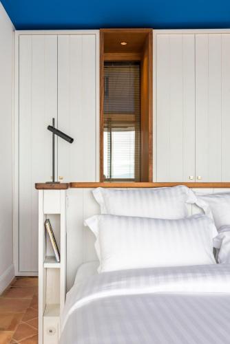 a white bed with a cross on top of it at Hôtel Le Bailli De Suffren in Rayol-Canadel-sur-Mer