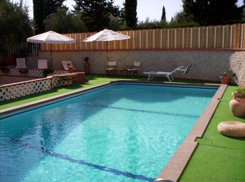 a swimming pool with a table and chairs and umbrellas at Casale Gli Ulivi in Orbetello